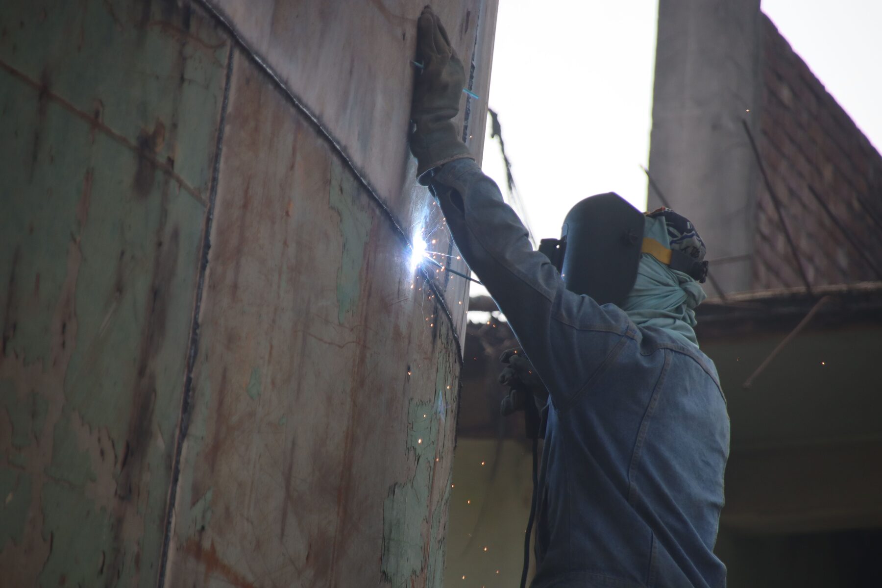 Marine welder performing structural work on a steel vessel hull